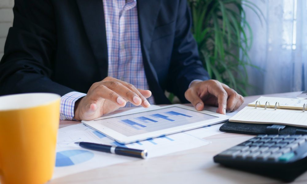 Man in office analyzing financial data on a digital tablet.