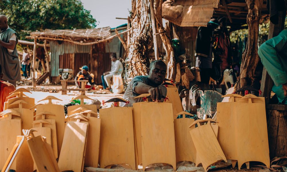 Skilled artisans handcraft traditional Nigerian items in a vibrant outdoor market setting, showcasing cultural craftsmanship.