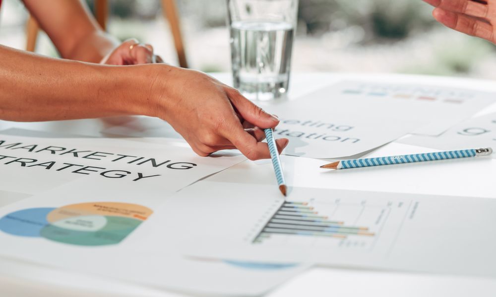 Hands discussing marketing strategy with charts in an office setting.