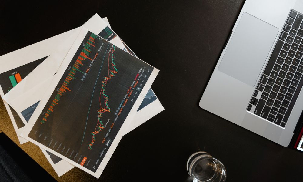 An overhead view of charts and graphs alongside a laptop on a black surface.