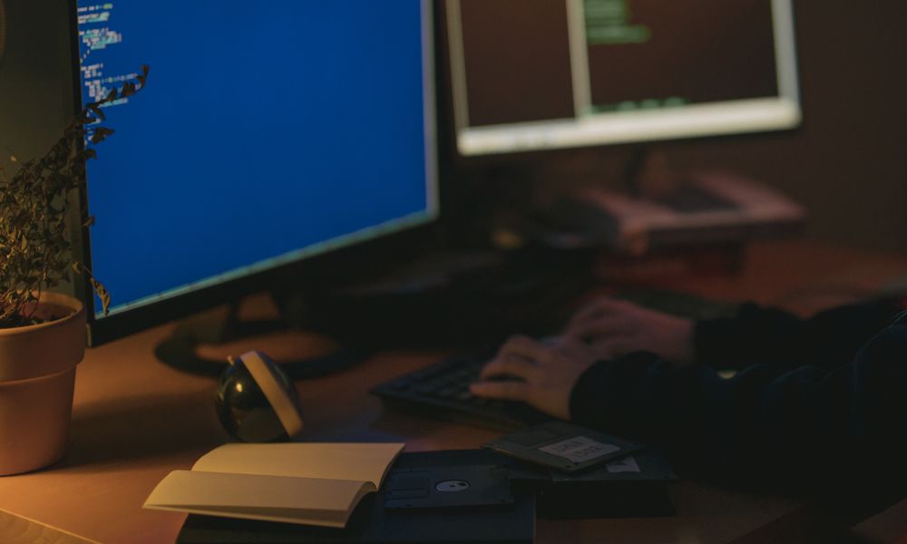Individual programming in a dimly lit room with dual monitors.