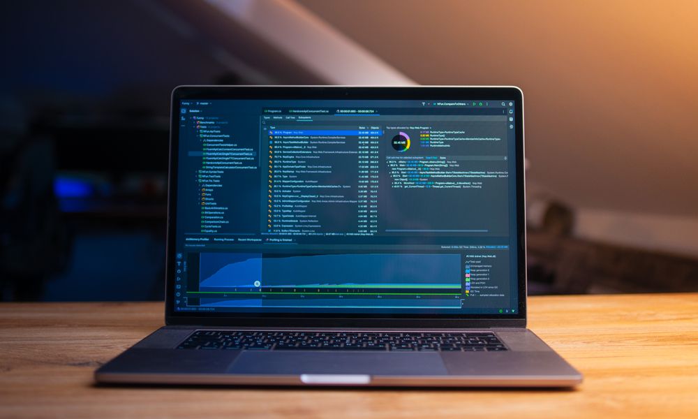 A laptop displaying code on a wooden desk, in a dimly lit workspace.