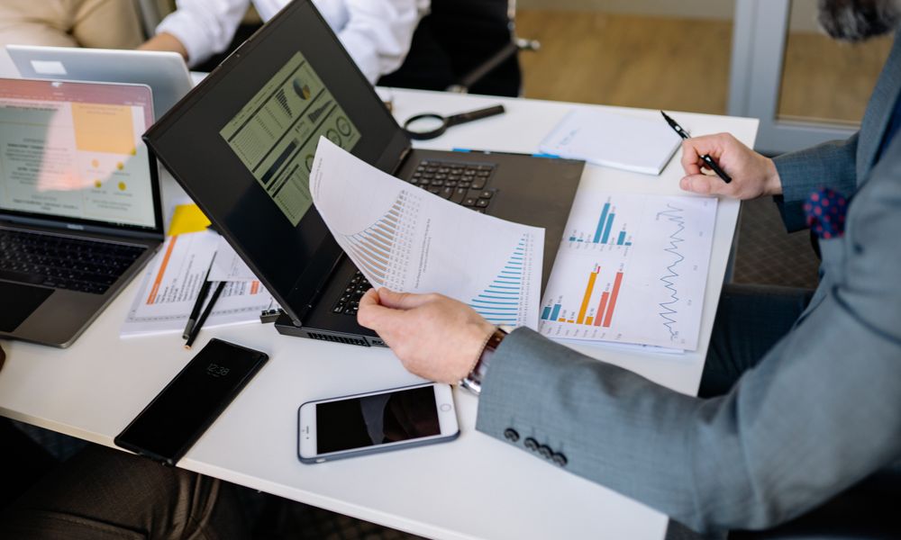 Professionals analyzing charts and graphs on laptops during a business meeting.