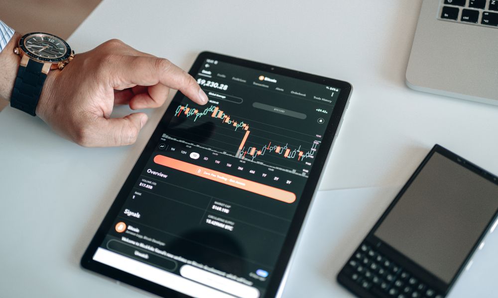 A person using a tablet to view and analyze a cryptocurrency market chart indoors.