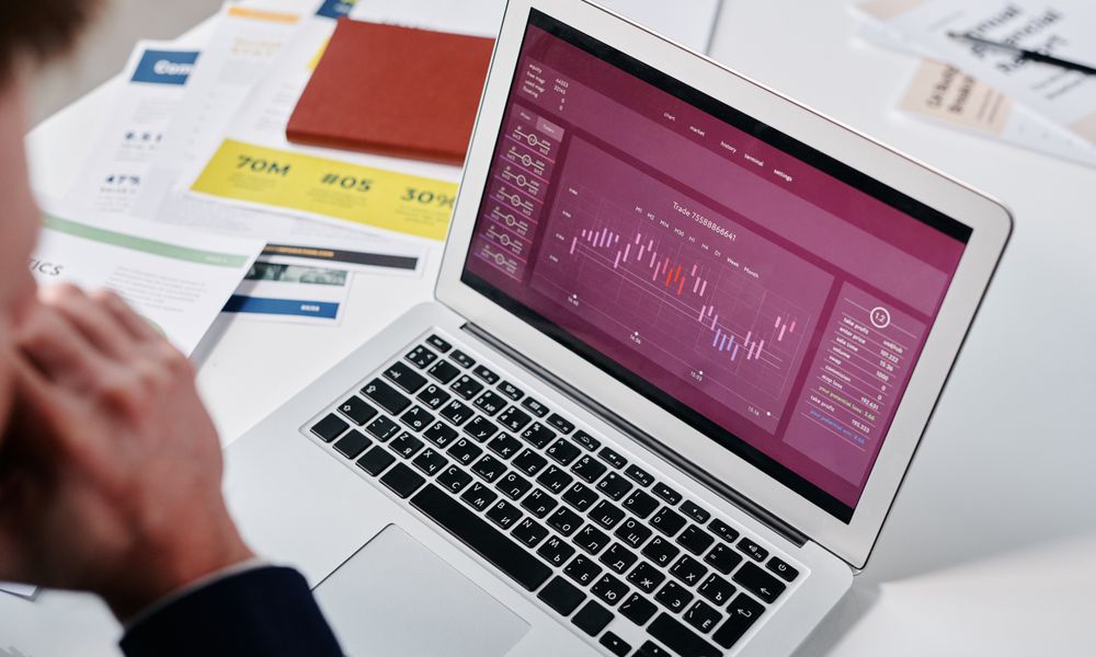Businessperson reviewing data analytics on a laptop screen in an office setting.