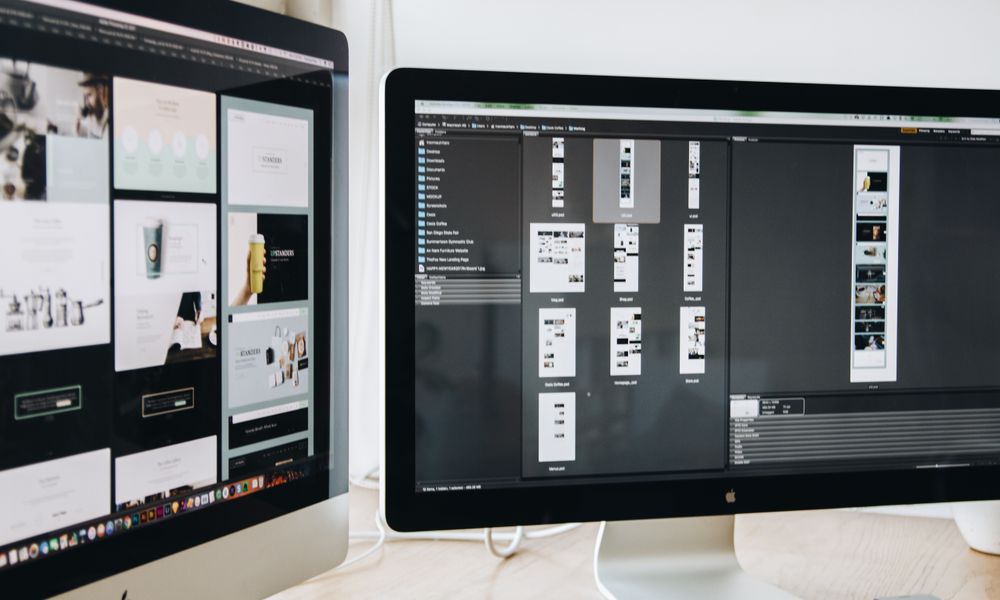 A modern workspace featuring dual computer monitors displaying web design projects, emphasizing technology and productivity.