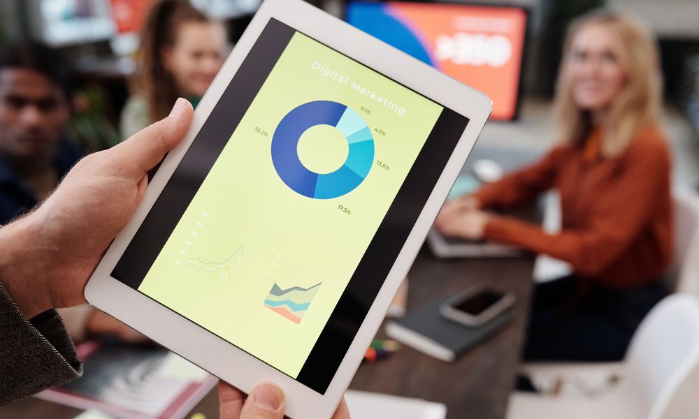 Business team reviewing digital marketing statistics on a tablet during an indoor meeting.
