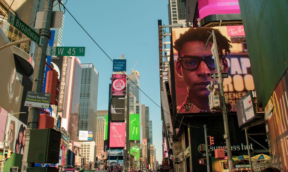 Lively daytime scene in Times Square, New York, showing towering skyscrapers and vibrant billboards.