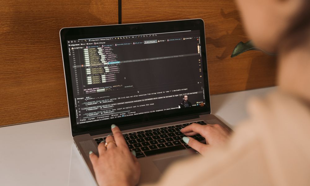 Close-up of a woman coding using a laptop in an office environment, showcasing modern technology.