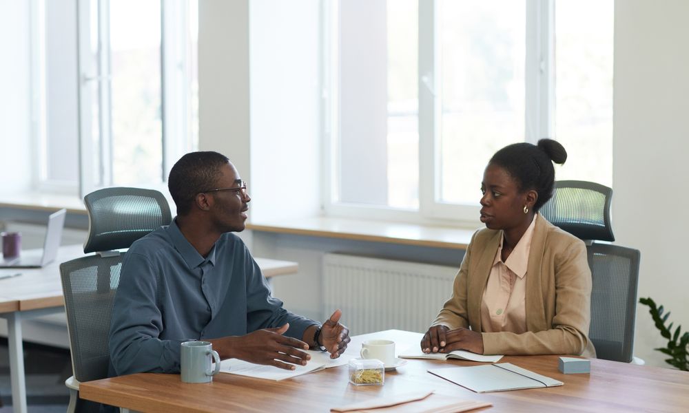 Two colleagues having a business conversation in a modern office setting.