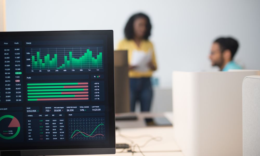 Modern office with financial trading screens and a diverse team discussing strategies.