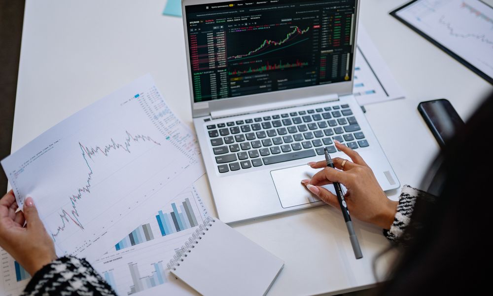 A detailed look at business analysis with a laptop displaying graphs and financial charts on a table.