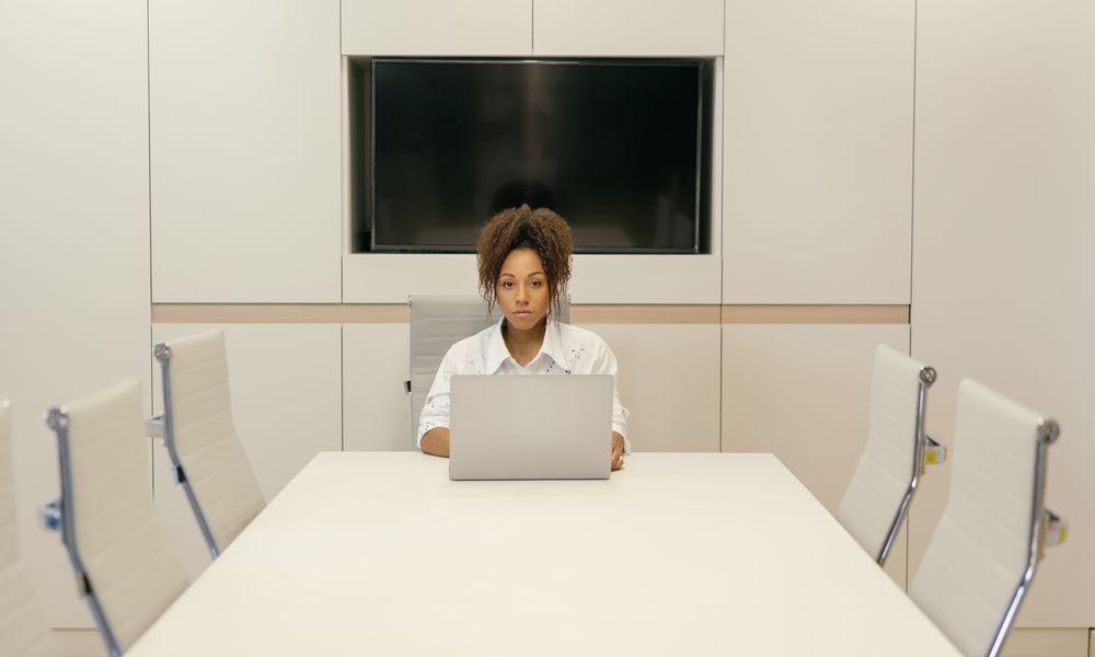 Professional woman using a laptop in a sleek conference room setting, focused and efficient.