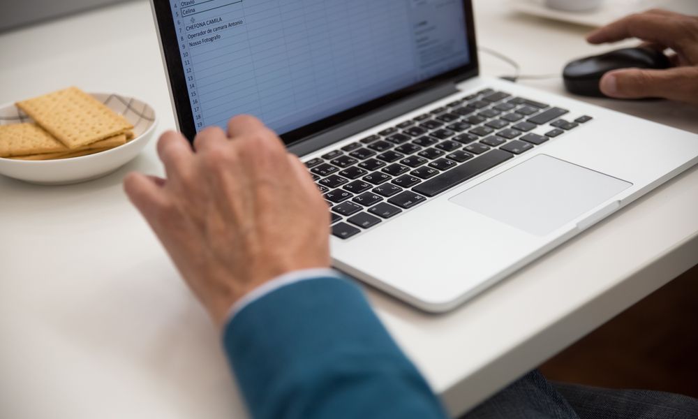 A person working on a laptop at a desk with snacks, emphasizing productivity and technology.