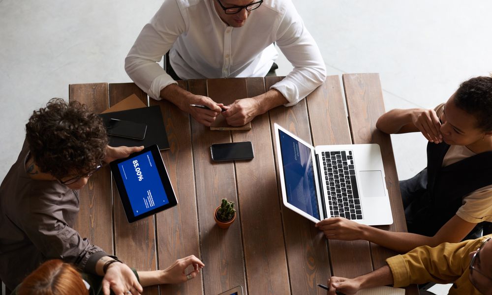 Top view of a diverse team collaborating with laptops and tablets in a modern workspace.