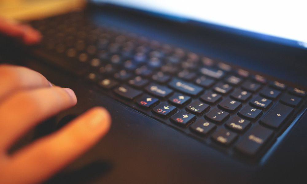 Blurred close-up of hands typing on a laptop keyboard, capturing a focused work moment.