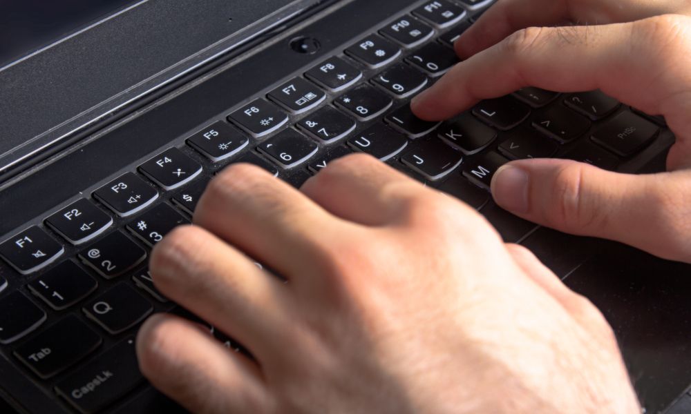 Detailed view of hands typing on a laptop keyboard, illustrating technology and work.