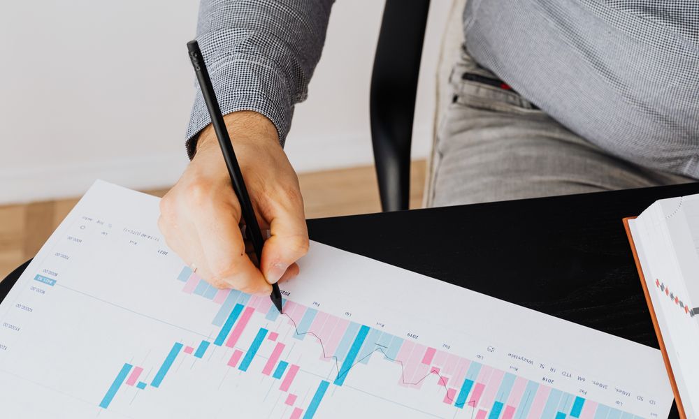 Detailed financial graph showing analysis by a person with a pen indoors.