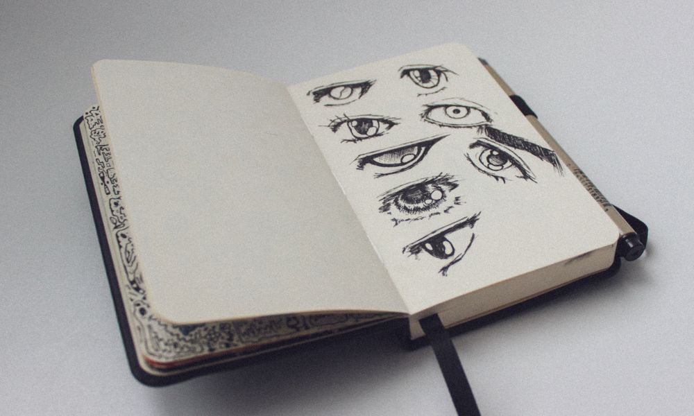 A sketchbook open to a page with artistic eye drawings, showcasing detailed sketches.