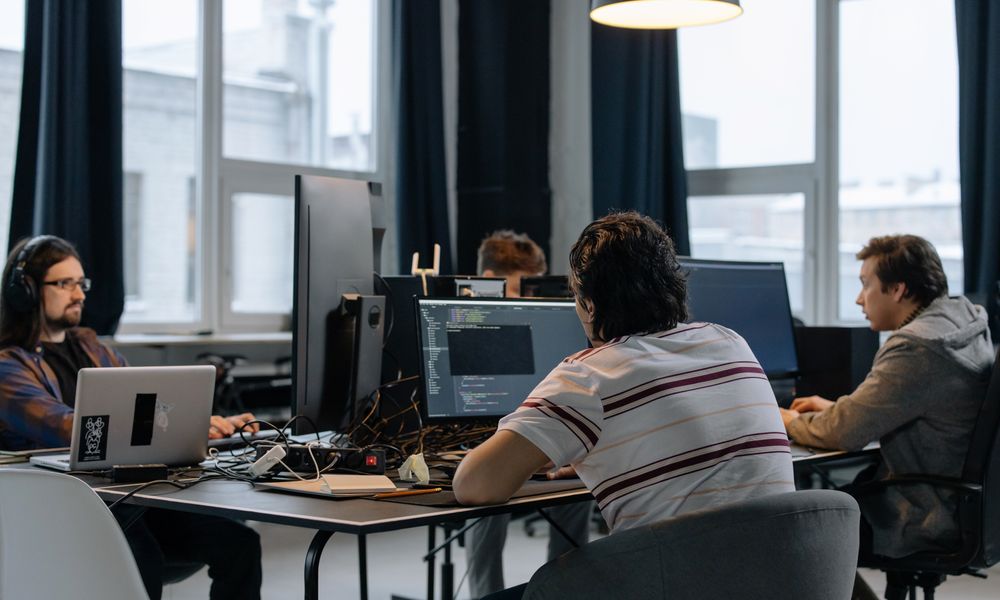 Team of developers working together on computers in a modern tech office.