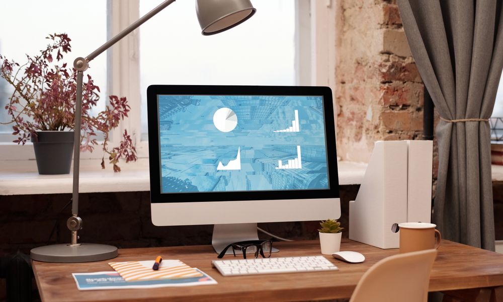 Clean and modern home office setup with computer, lamp, and decor. Ideal for productivity in a contemporary workspace.