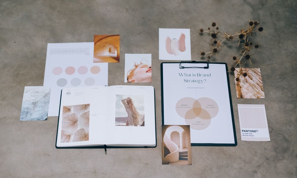 A flat lay of branding elements with color palettes and strategic planning documents on a concrete surface.