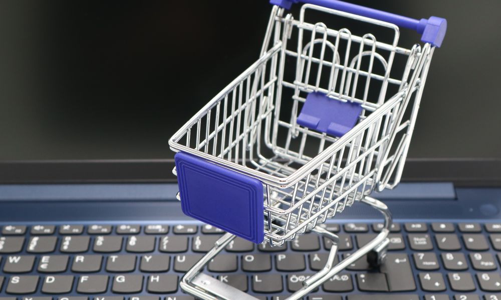 A mini shopping cart placed on a laptop keyboard, symbolizing online shopping and digital retail.