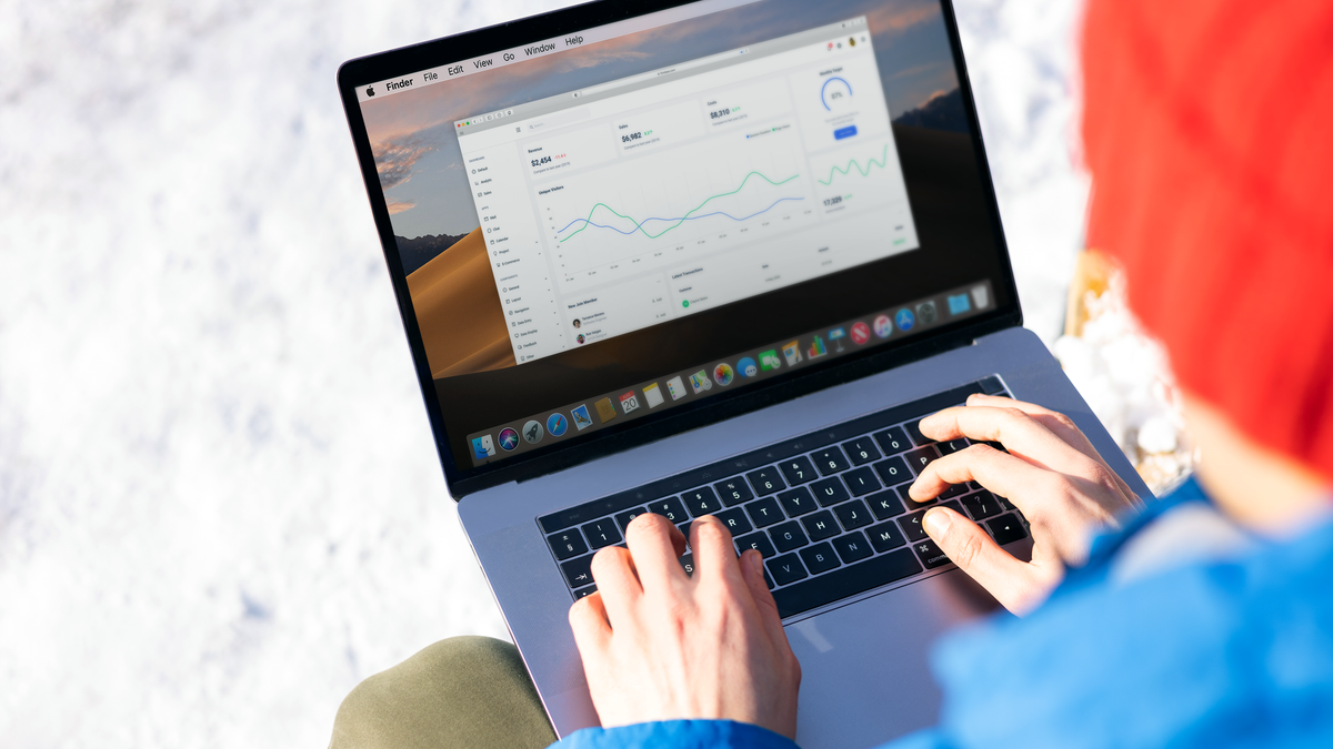 A person in a blue jacket analyzing business analytics on a laptop outdoors during winter.