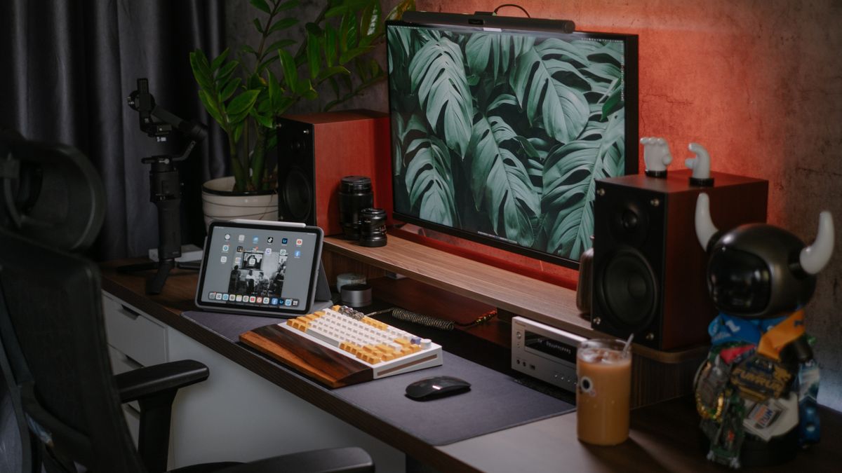 A stylish home office setup featuring a monitor, tablet, speakers, and decorative items. Ideal for tech enthusiasts.
