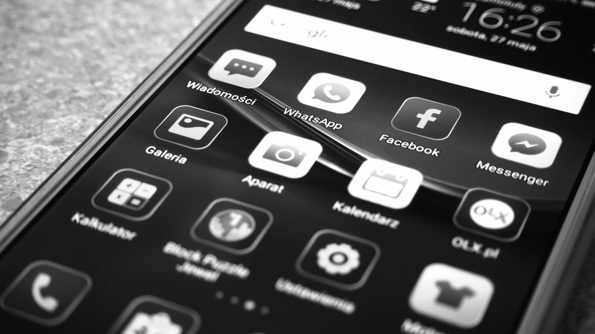 Black and white photo of smartphone showing popular app icons like Facebook and WhatsApp.