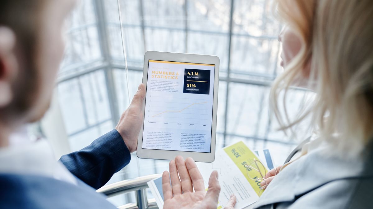 Business professionals discussing analytics on a tablet in a modern office setting.