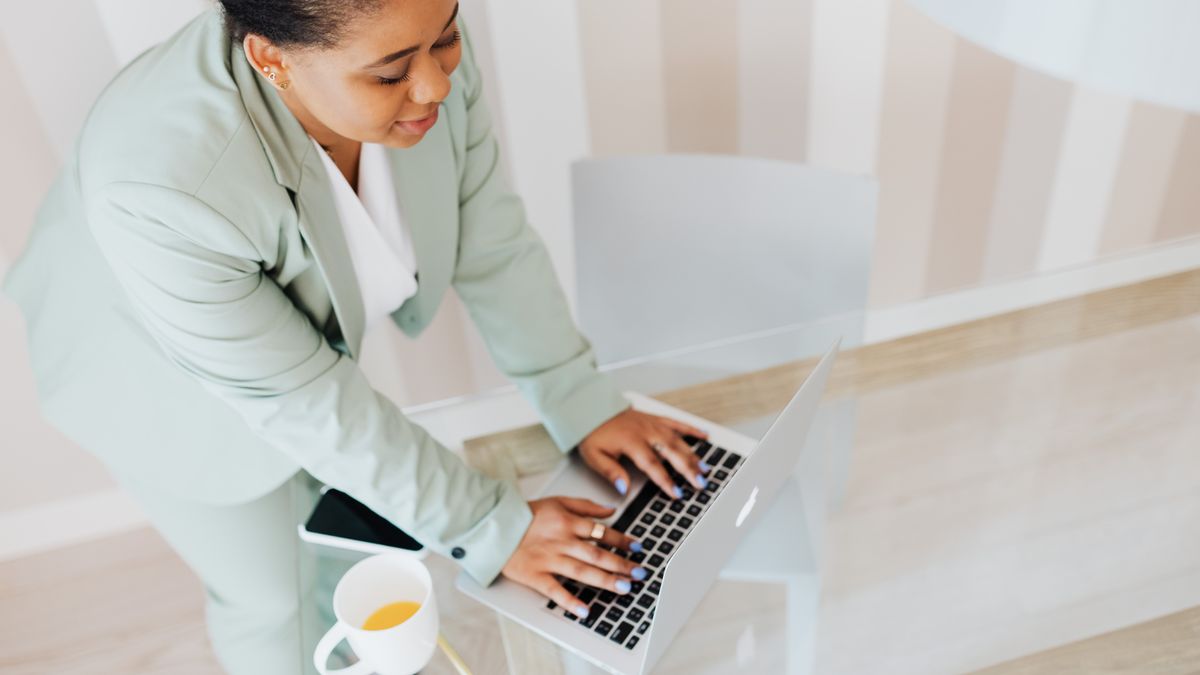 Businesswoman in a suit working on a laptop, illustrating modern professional life.