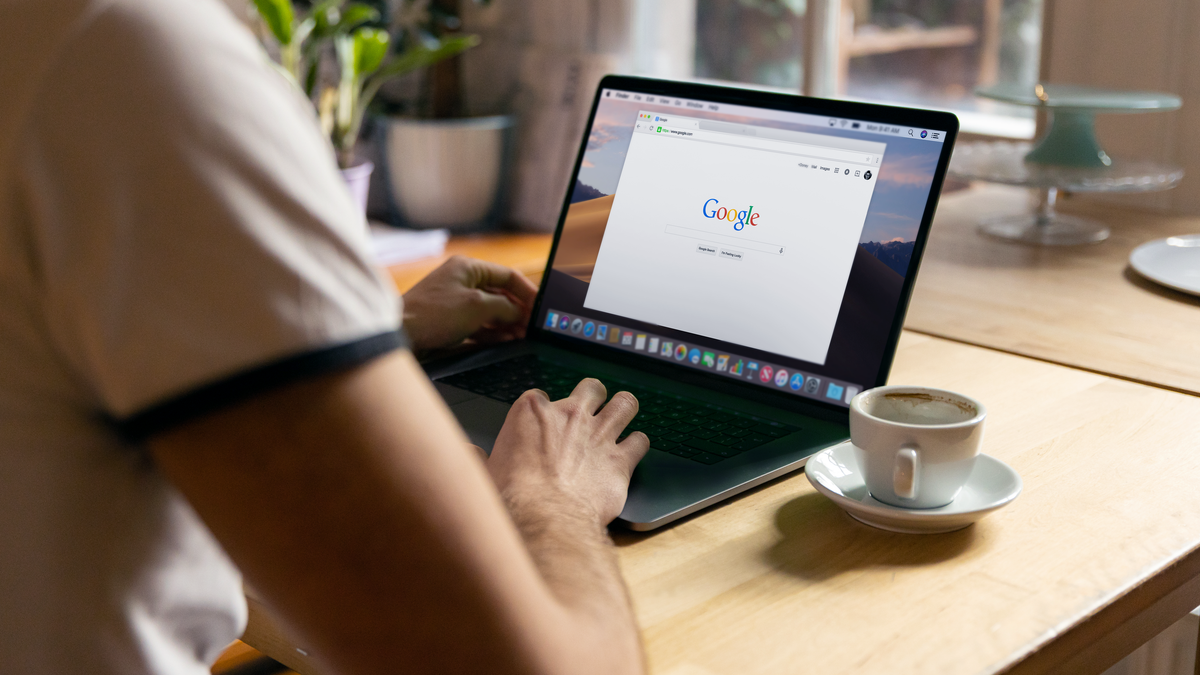 A person working on a laptop in a cozy indoor setting with a coffee cup on the table.
