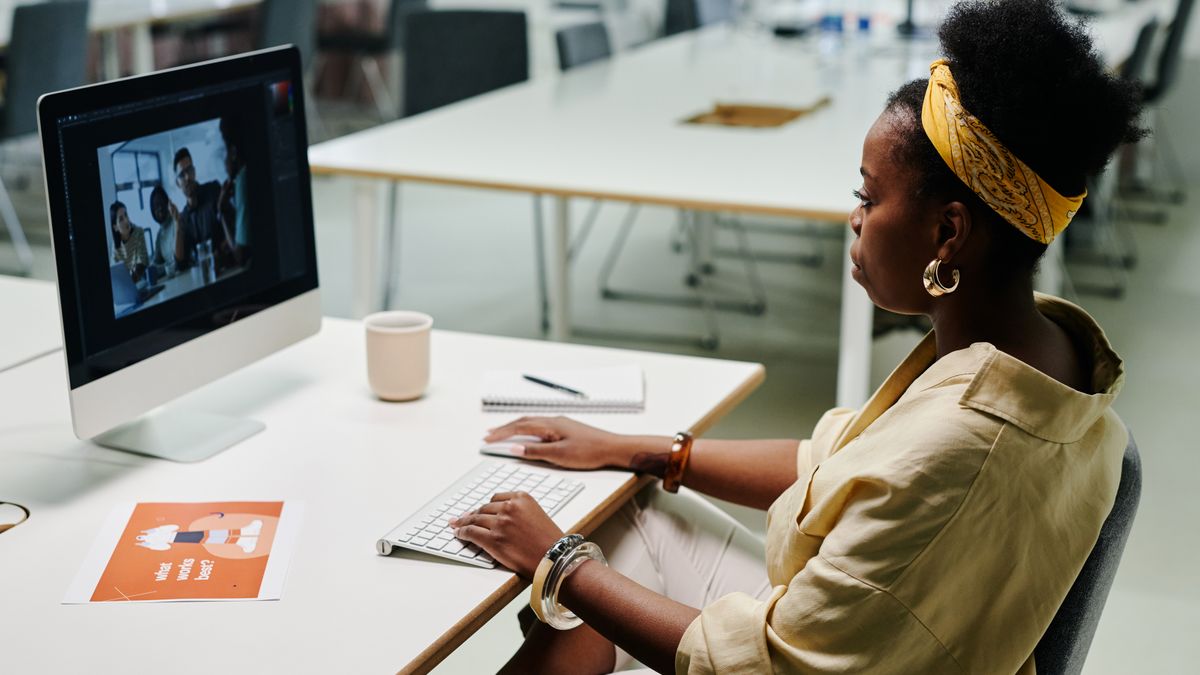 Young black woman using computer for video editing in a modern office setting.