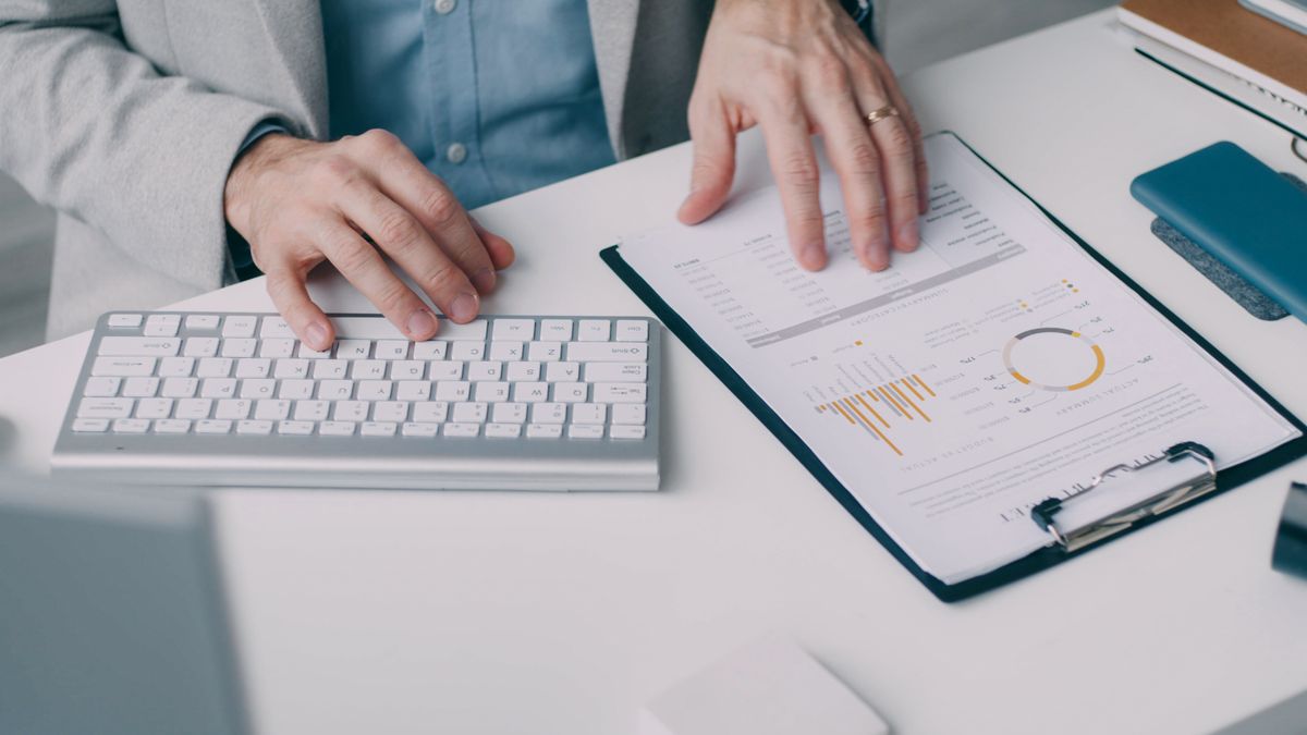 A man working with a financial report and keyboard in an office setting.