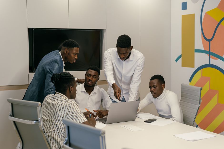 Group of diverse men in a modern office engaged in a productive meeting over a laptop.
