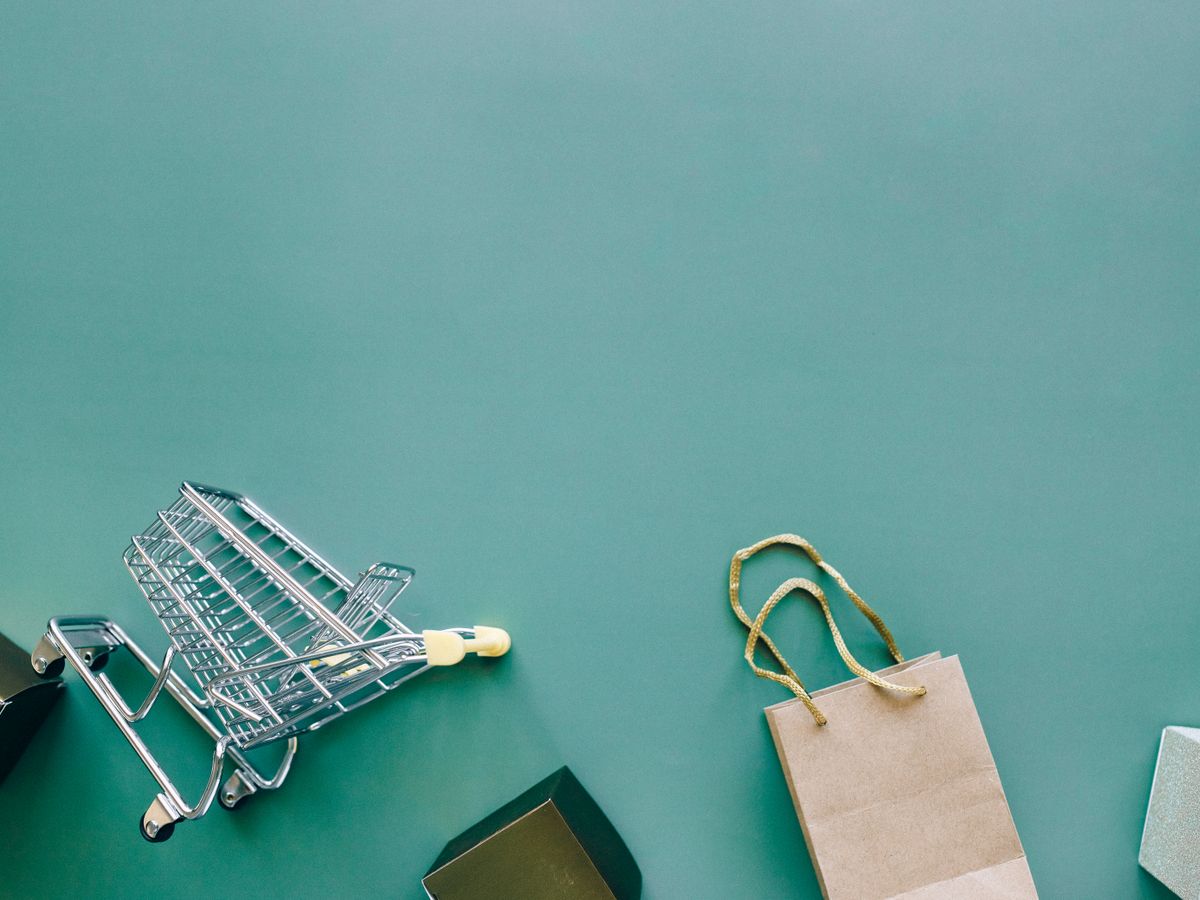 Top view of a shopping cart and bag on a blue background, ideal for retail themes.